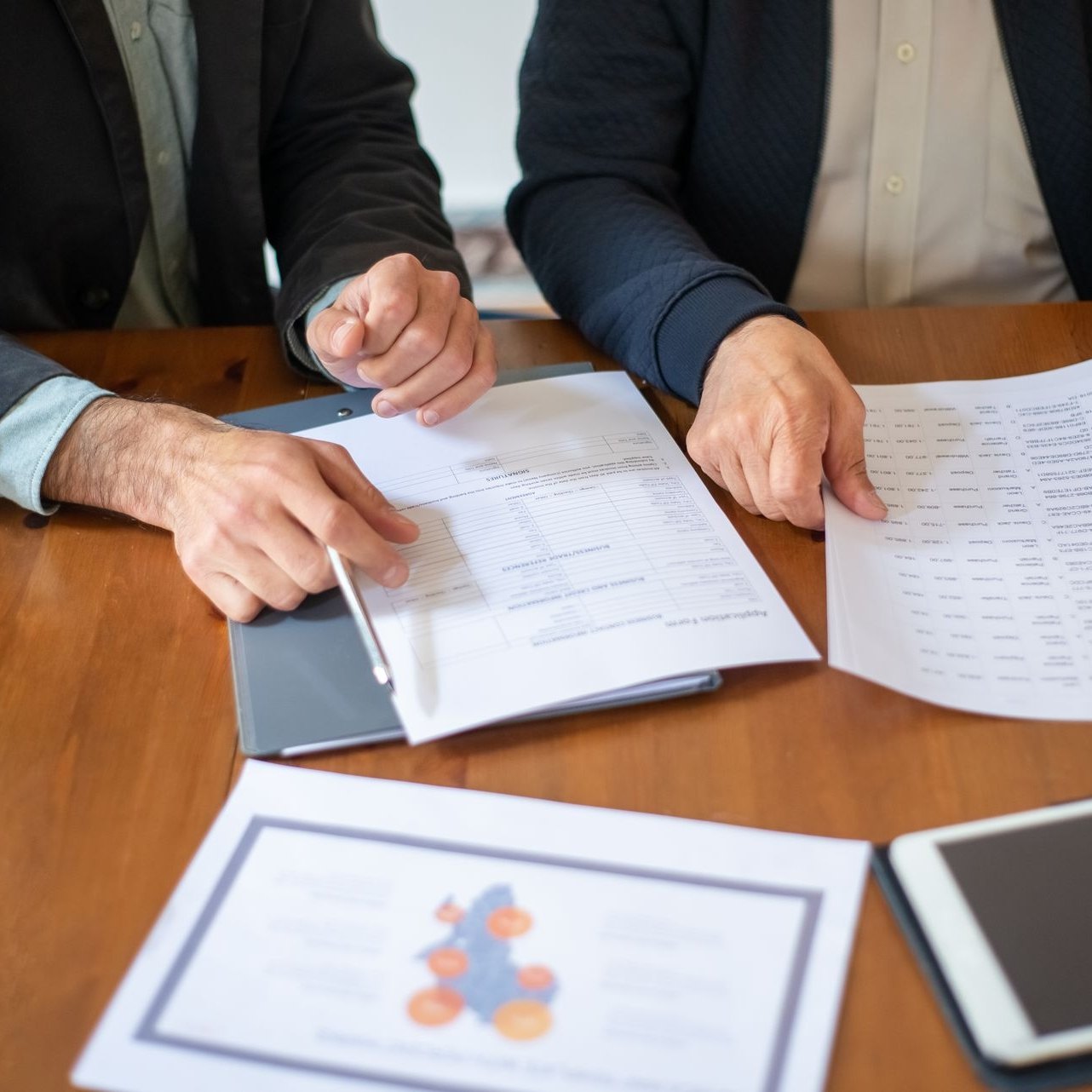 Parenting plan documents and a tablet on a table between two parents