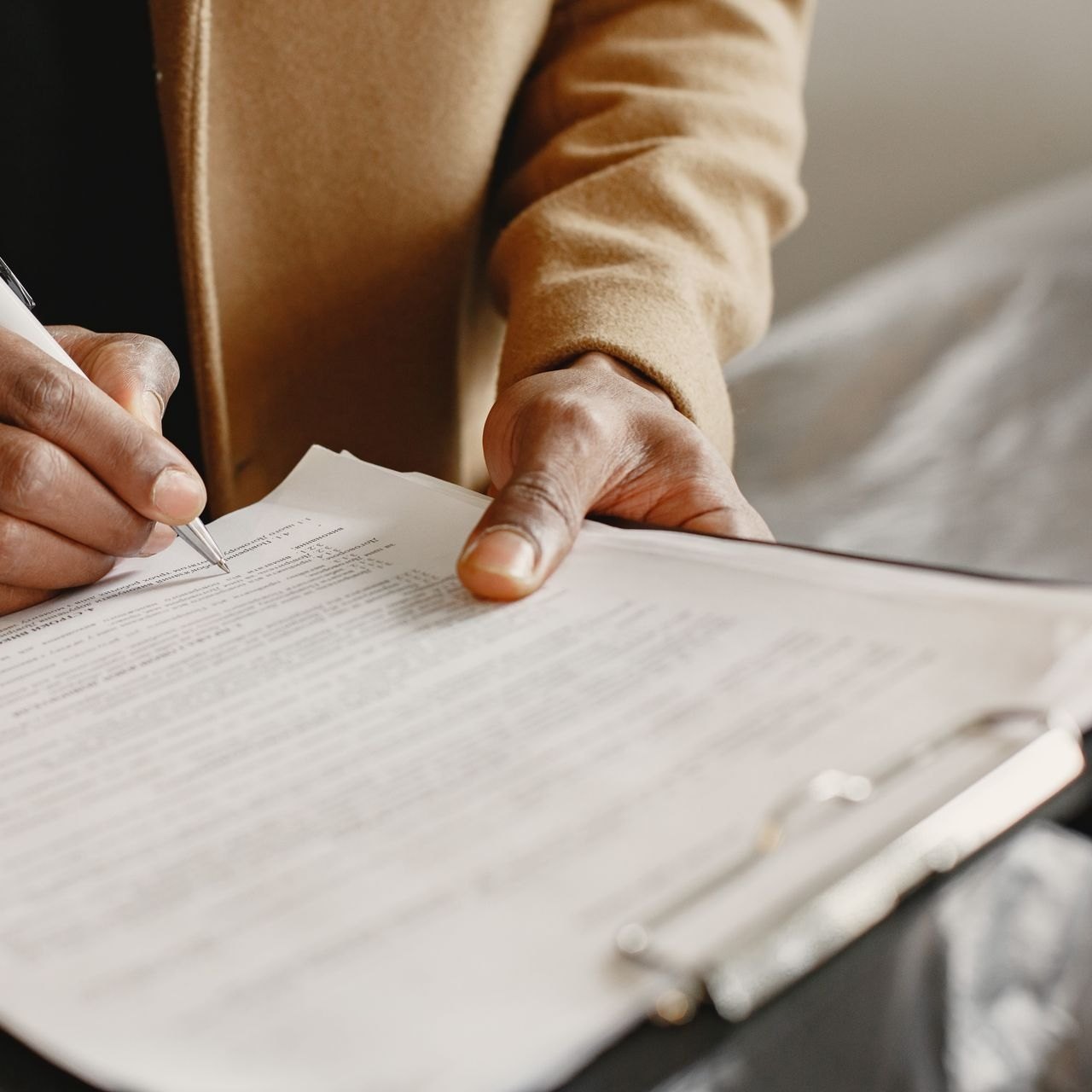 Two hands signing an agreement side by side at an office desk
