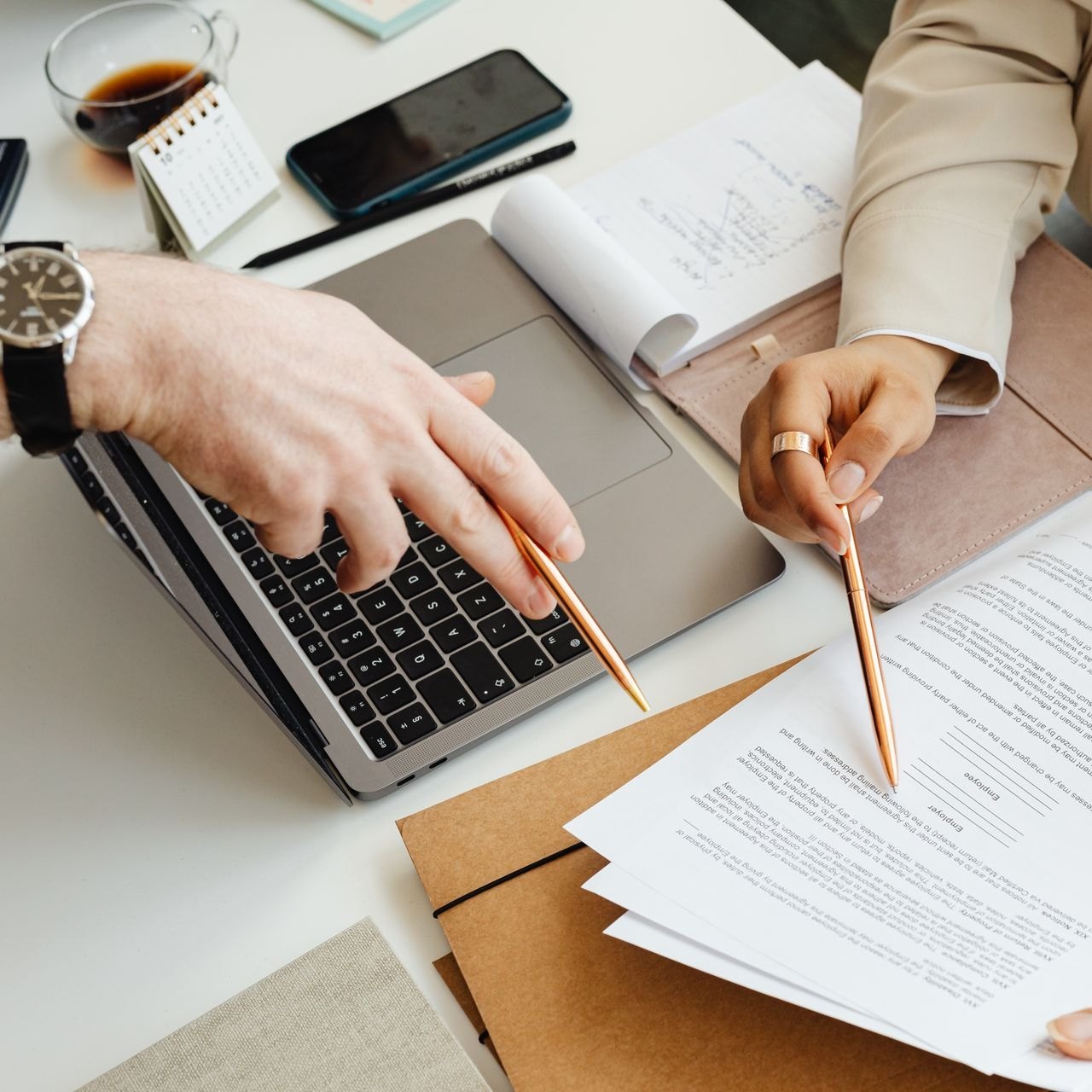 Printed legal filings beside a laptop with a finger marking a detail